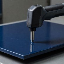 Handheld coating thickness probe positioned on a painted metal panel
